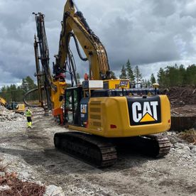 Gul cat gravemaskin på grusvei i skog